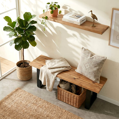 Wooden bench with pillows and a basket in a room with a plant and shelf.